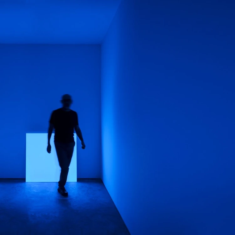 Uomo sfocato in ombra cammina in una stanza blu con luce soffusa